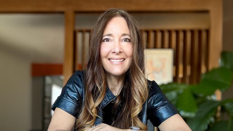 Dena Blevins sitting indoors with wooden décor in the background.