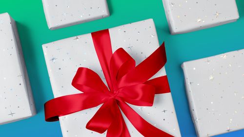 White gift boxes with a red ribbon angled on a green and blue gradient background