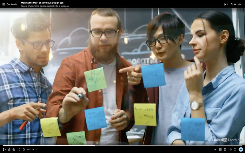 Four smart looking people discussing ideas around a whiteboard with post it notes