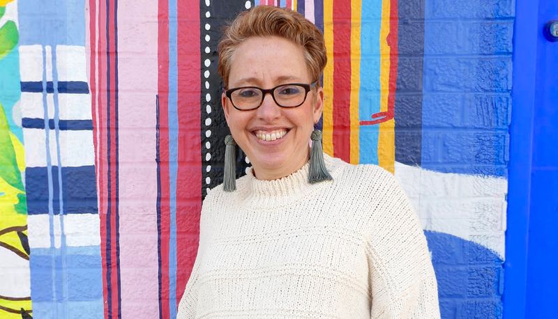 Portrait of Emily Cohen standing infront of colored wall