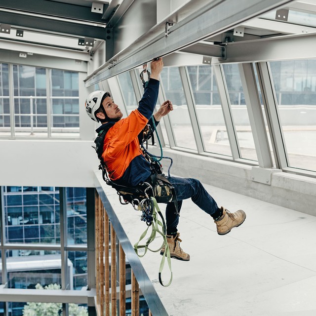 Worker utilizing a rigid rail system for fall protection