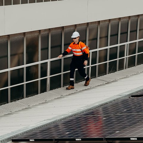 a man wearing a hard hat is walking on a safety walkway