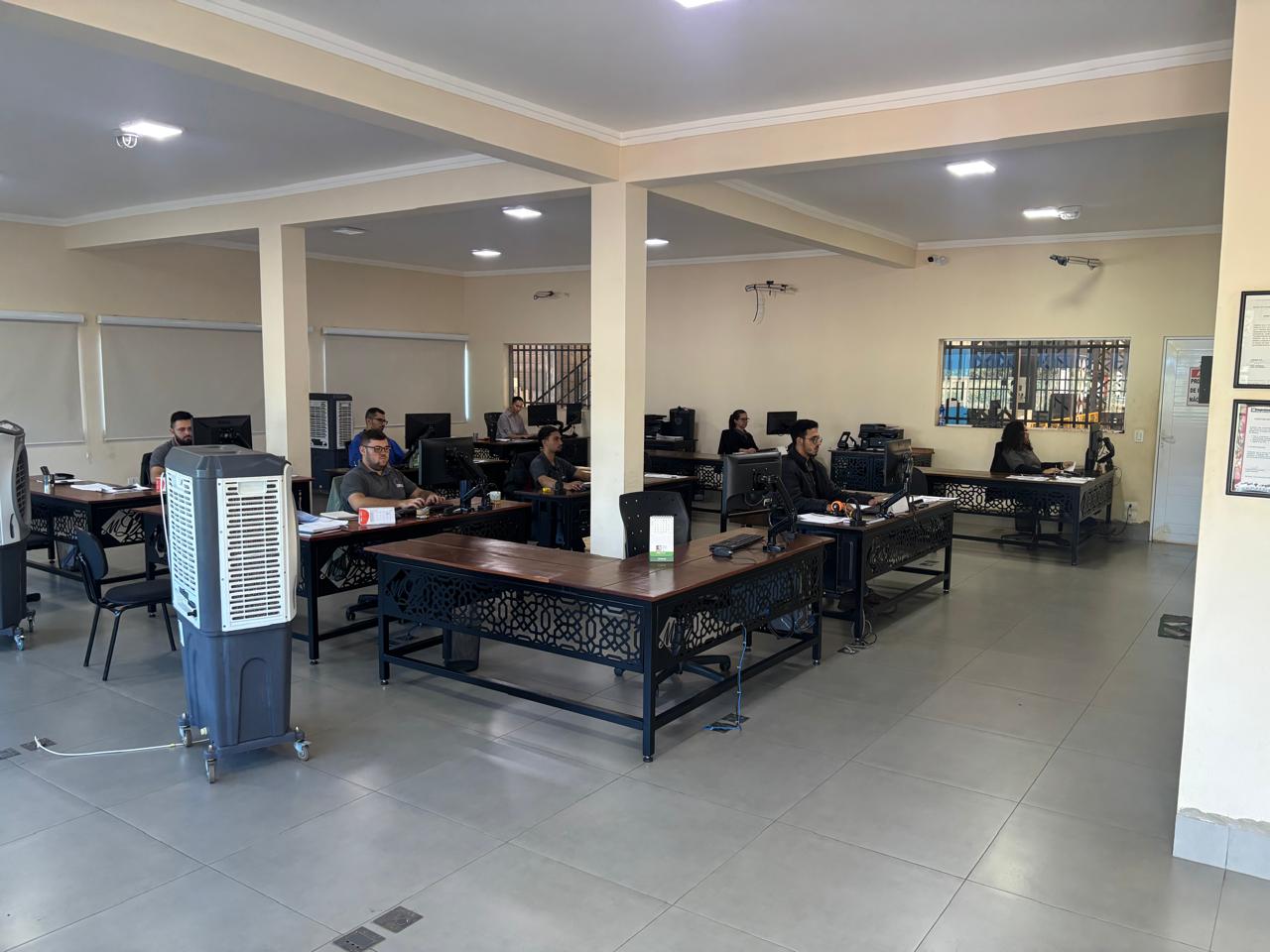 Escritório de uma empresa com várias meses e pessoas trabalhando.