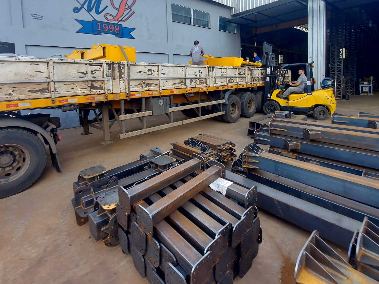 Vigas de aço organizadas em pátio industrial.