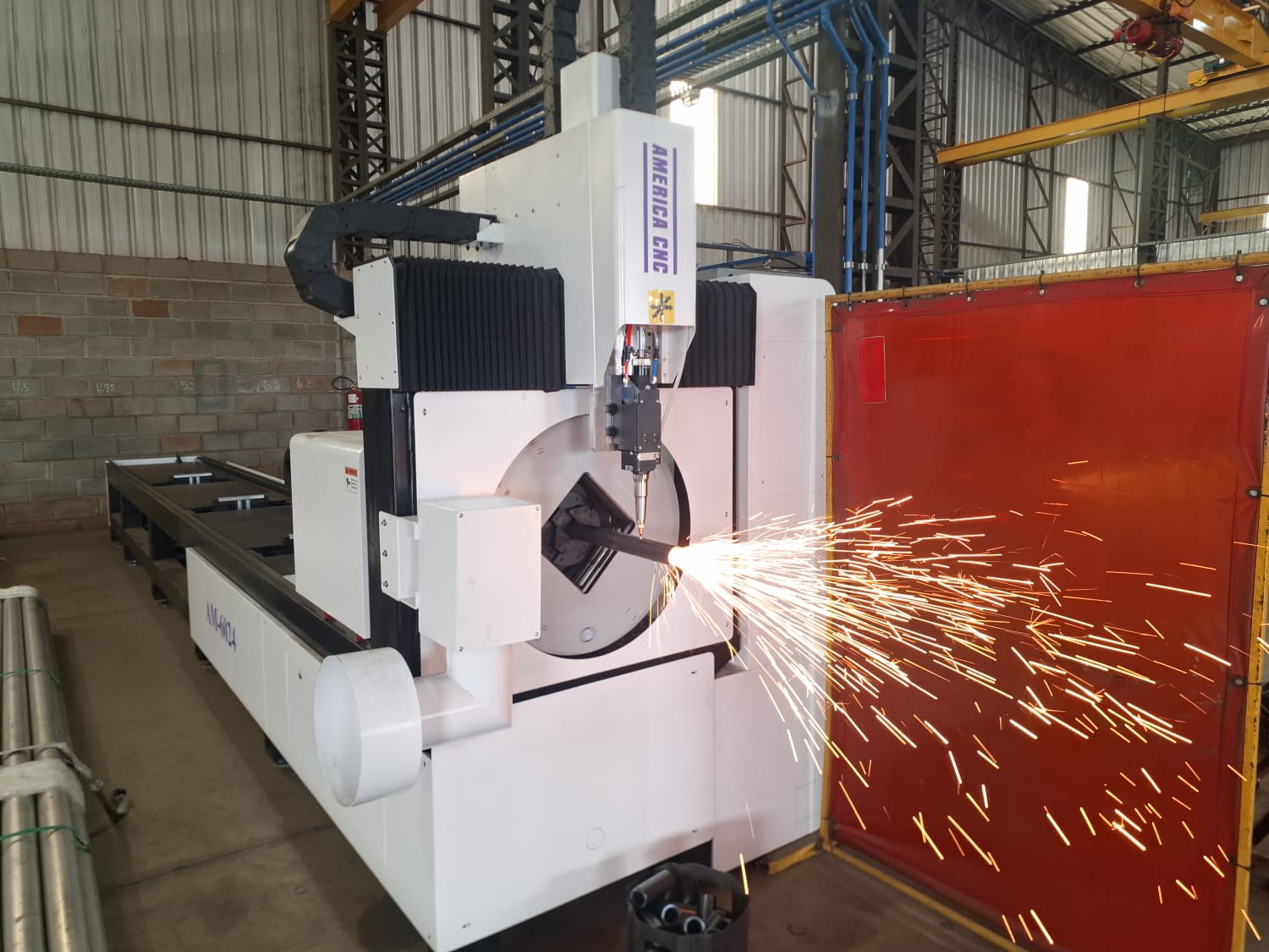 Máquina CNC realizando corte a laser em peça metálica cilíndrica, com faíscas brilhantes em oficina industrial.