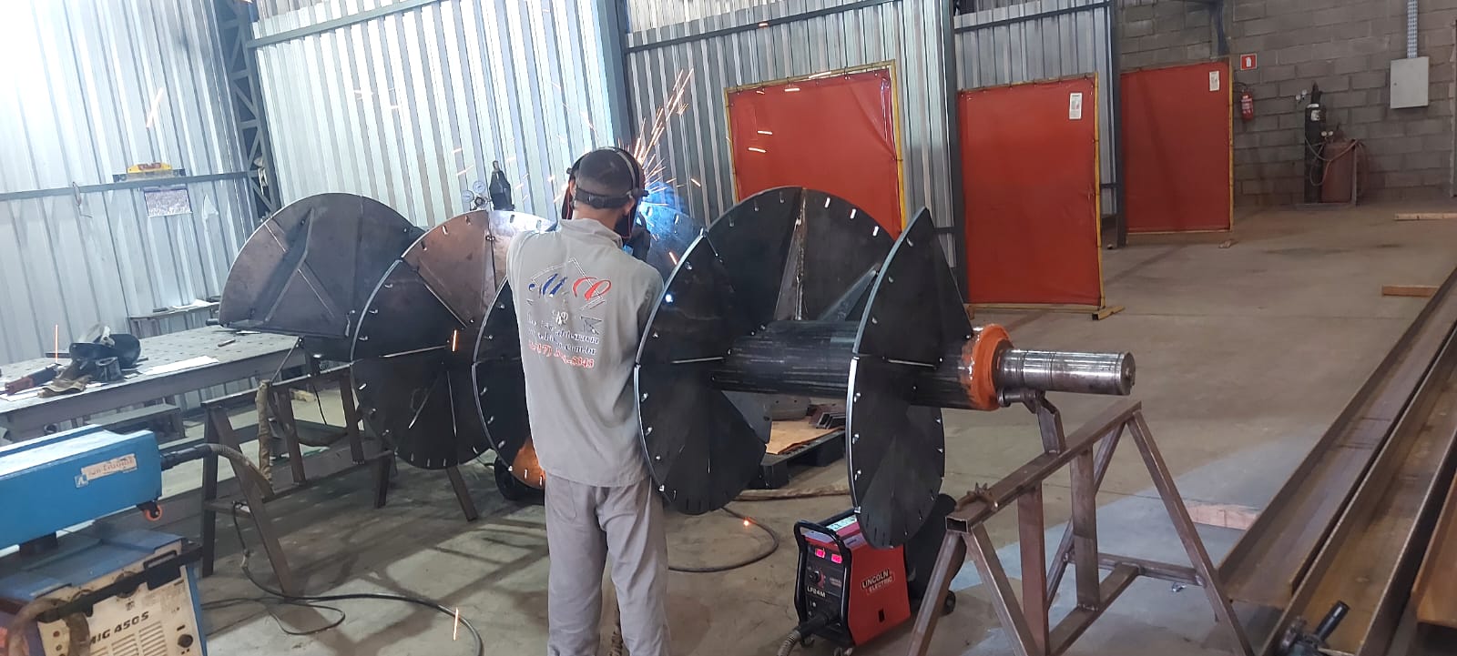 Soldador com máscara trabalhando em peça metálica.