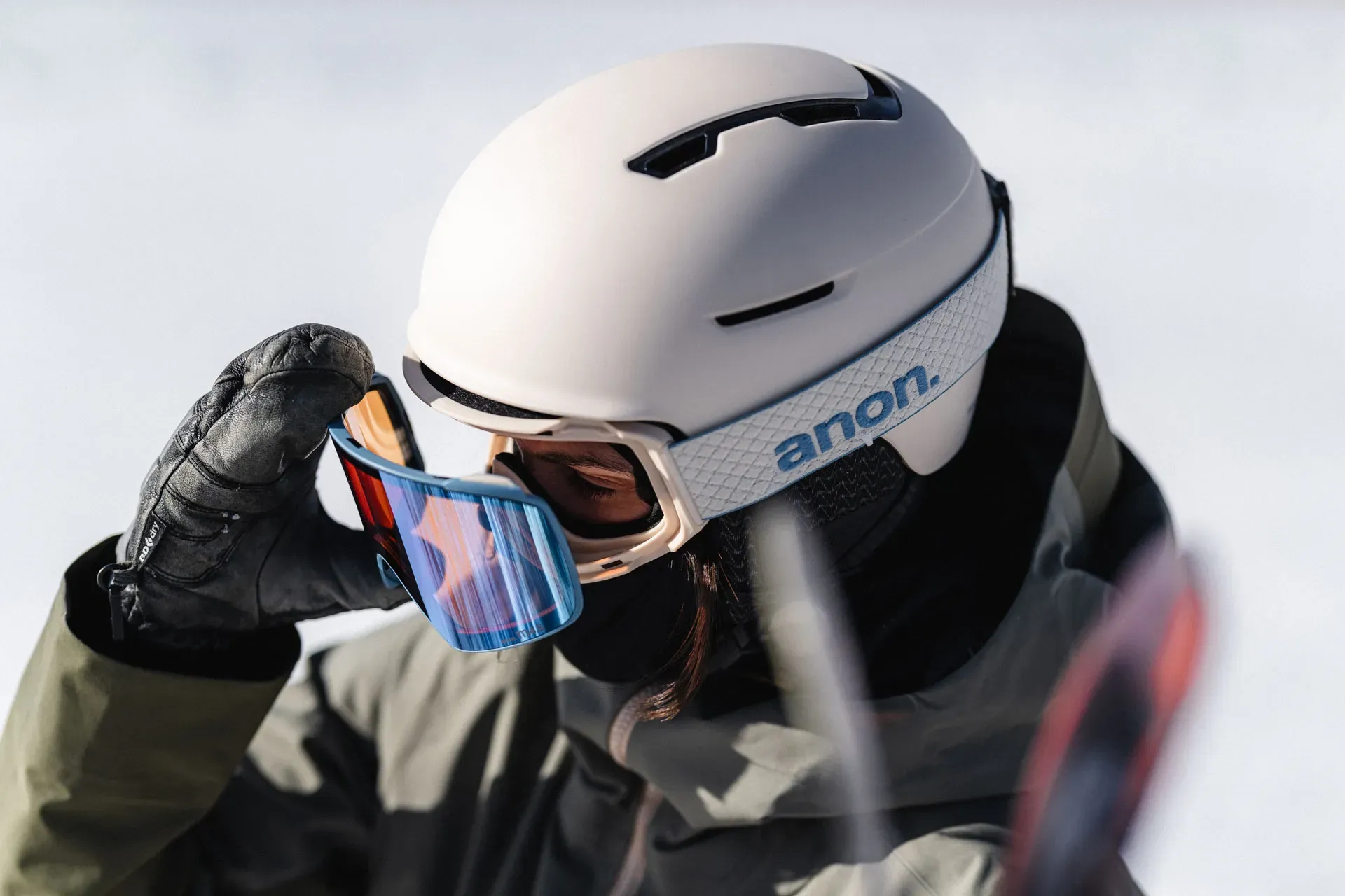 Woman pulling her Anon snow goggles off and switching the visor lens