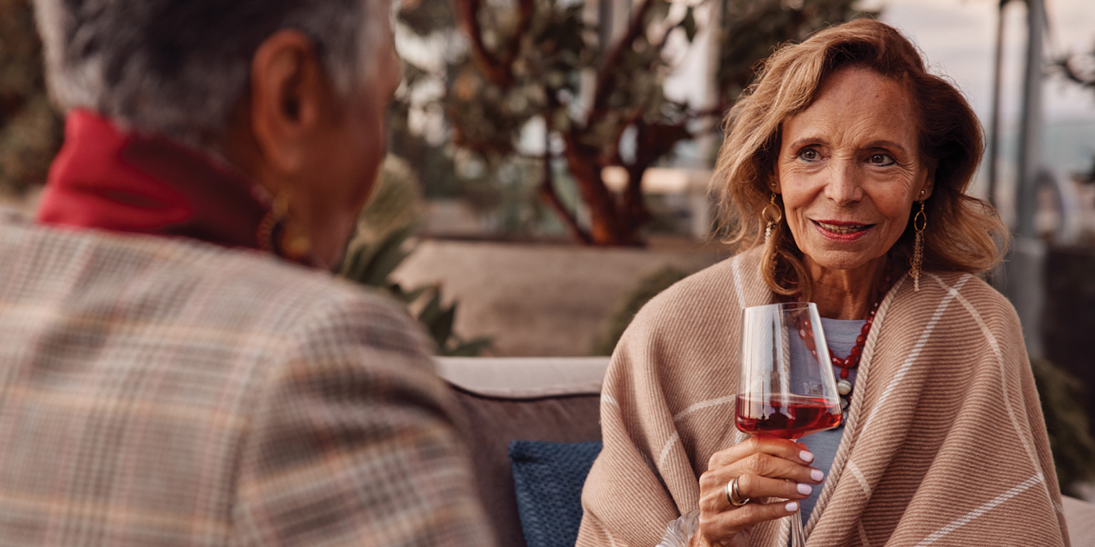 Two Coterie residents talking, drinking wine and bundles up in an outdoor space.