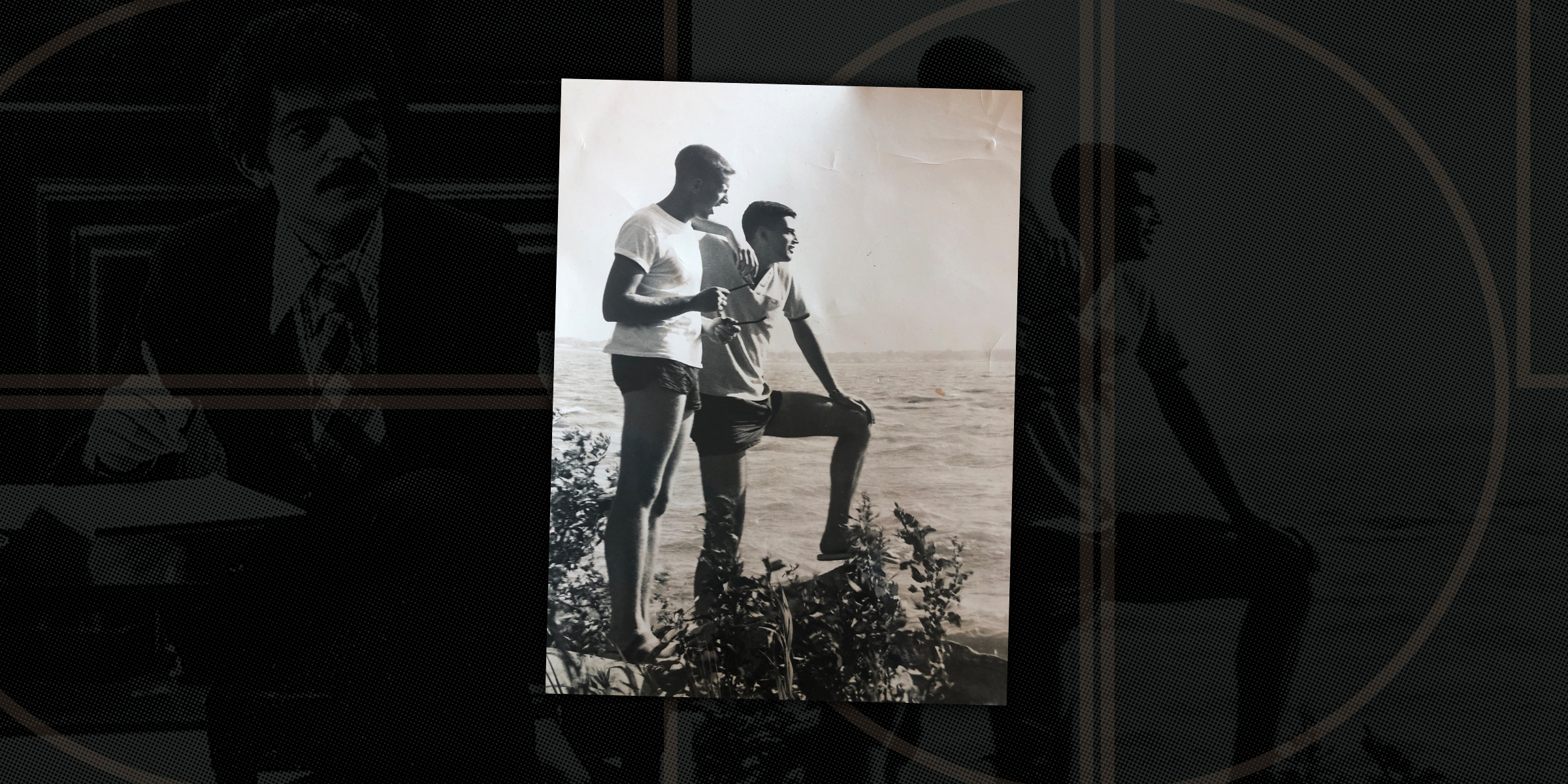 An old black-and-white photograph of two young men standing on a shoreline, looking out over the water. One stands with a drink in hand while the other rests one foot on a rock. The photo is displayed against a dark, patterned background featuring faint, stylized images of people.