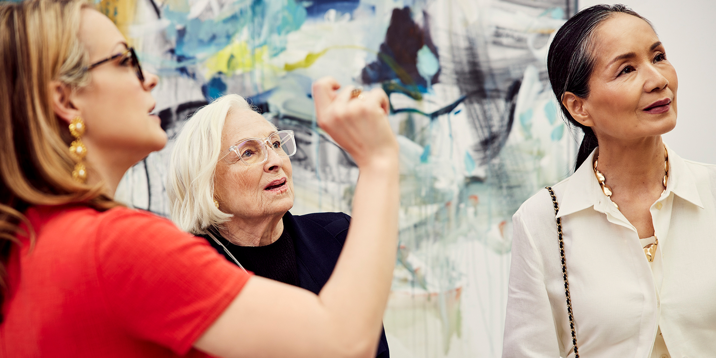 Two older women admiring artwork with the help of a museum docent