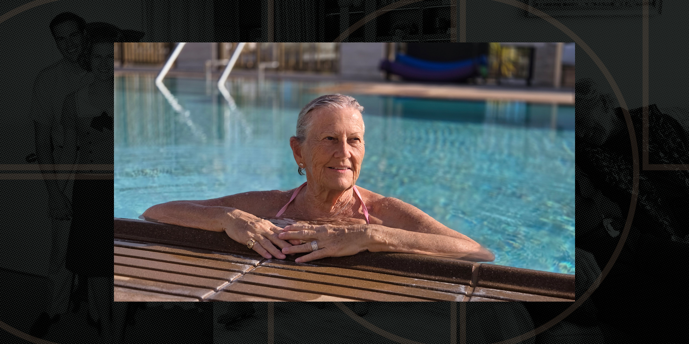 Older woman relaxing in a swimming pool, resting her arms on the edge, with a gentle smile and clear blue water in the background.