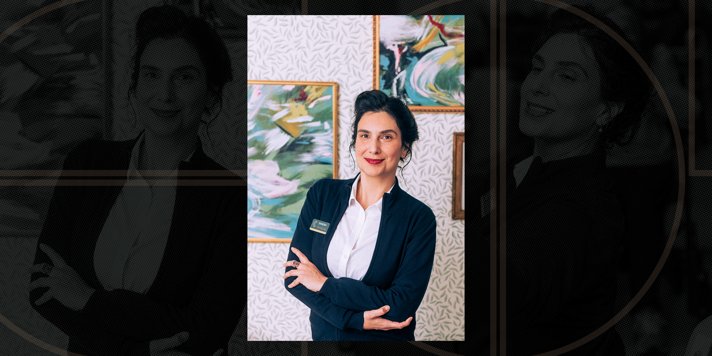 Memory Care Resident Engagement Specialist Sandra R, standing confidently with arms crossed, in front of abstract paintings.