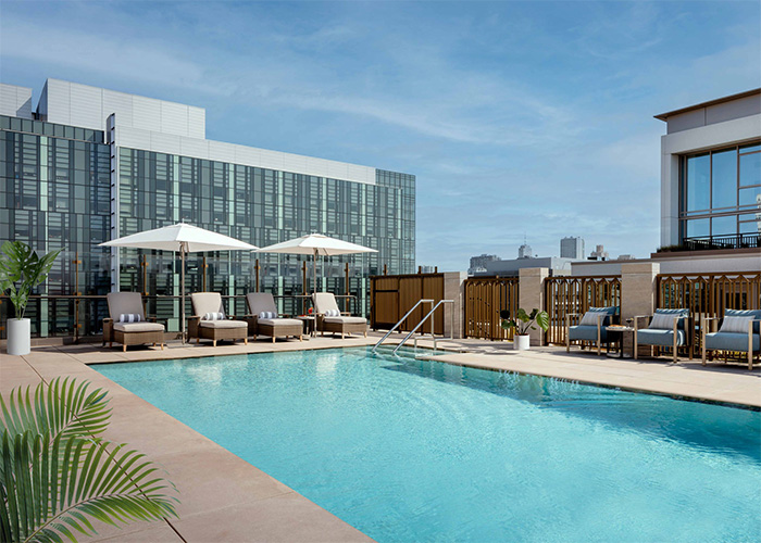 Rooftop pool and terrace with sun chairs and umbrellas.