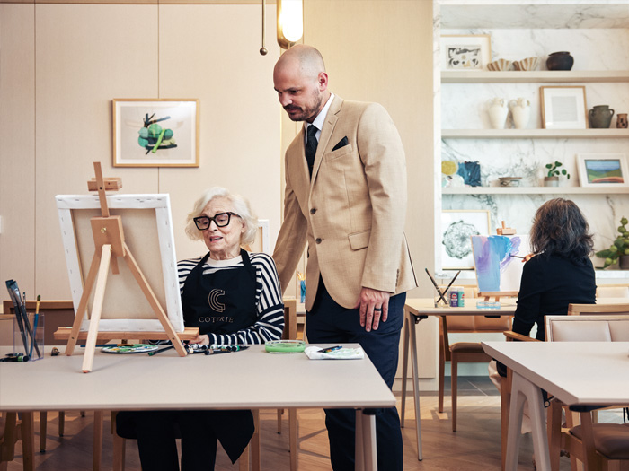 Coterie GM socializing with Coterie resident who is painting on a canvas