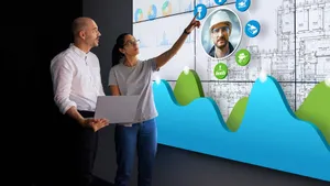 Two Construction Project Managers looking at models on computers and discussing streamlining processes with construction project management software.