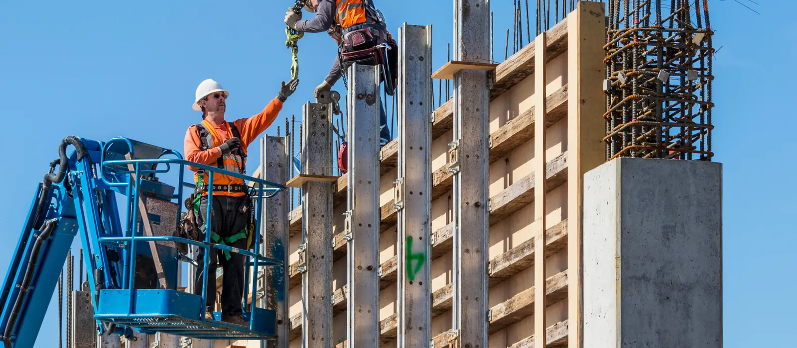 Construction workers standing high on a structure demonstrating the need for construction site safety.