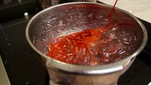 A lobster being blanched in a stainless steel pot filled with ice water