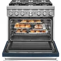 Stainless steel oven with open door, showing trays of pastries and a pie inside. Six-burner stovetop visible on top.