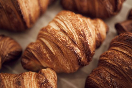 Freshly baked croissants with golden, flaky layers are scattered on parchment paper.