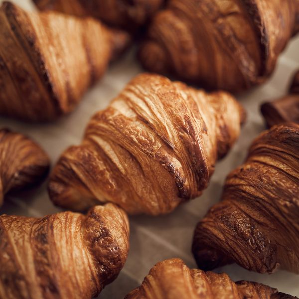 Freshly baked croissants with golden, flaky layers are scattered on parchment paper.