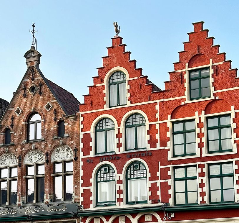 Historic brick buildings with stepped gables and ornate windows against a clear blue sky.