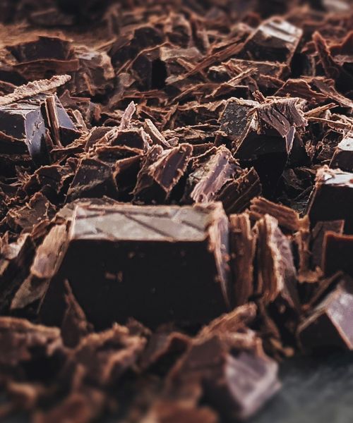 Close-up of dark chocolate pieces and shavings on a work surface during a chocolate-making workshop in Turin.
