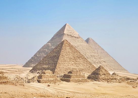 The Great Pyramids of Giza in Egypt under a clear blue sky, showcasing their ancient, majestic structure in a desert landscape.