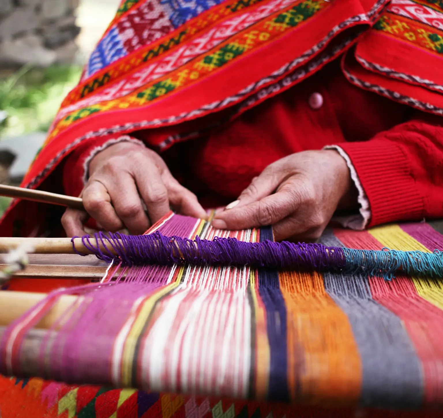 a women weaving an array of colorful yarn