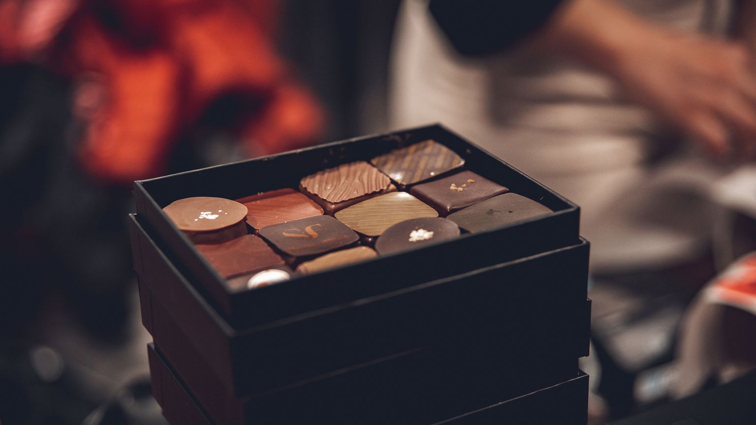 A close-up of an open box containing assorted gourmet chocolates, each with unique designs and textures.