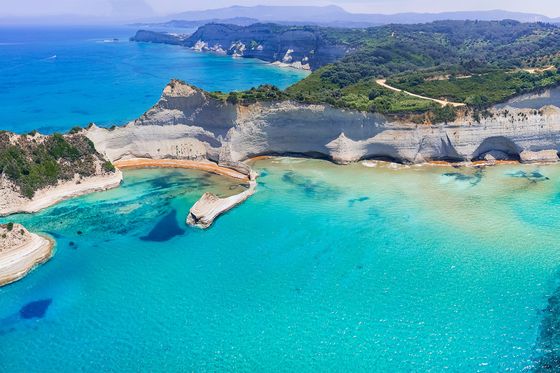 Aerial view of a beautiful coastal landscape with turquoise waters, sandy beaches, and white cliffs covered in green vegetation.