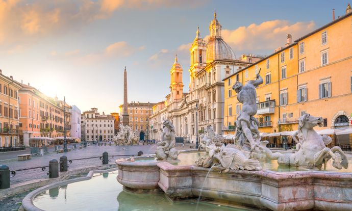 Sunlit Piazza Navona in Rome, featuring the Fountain of Neptune with surrounding historic buildings and a cloudy sky.