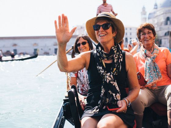 women riding a gondola, smiling and waving