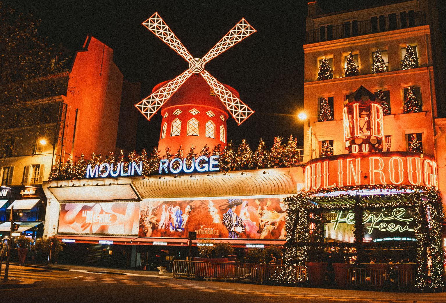 The glowing facade of Moulin Rouge decorated with Christmas trees and lights