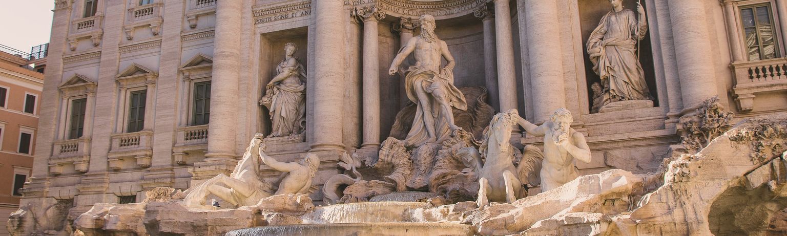 The Trevi Fountain in Rome, adorned with intricate sculptures, cascading water, and classical architecture under sunlight.
