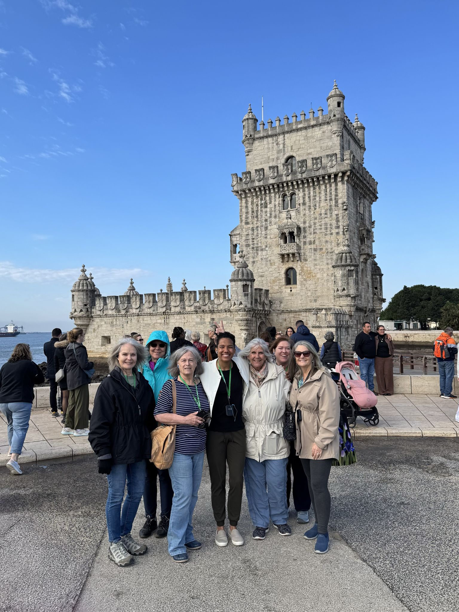 A group of people posing in front of the historic Belém Tower with a clear blue sky in the background.