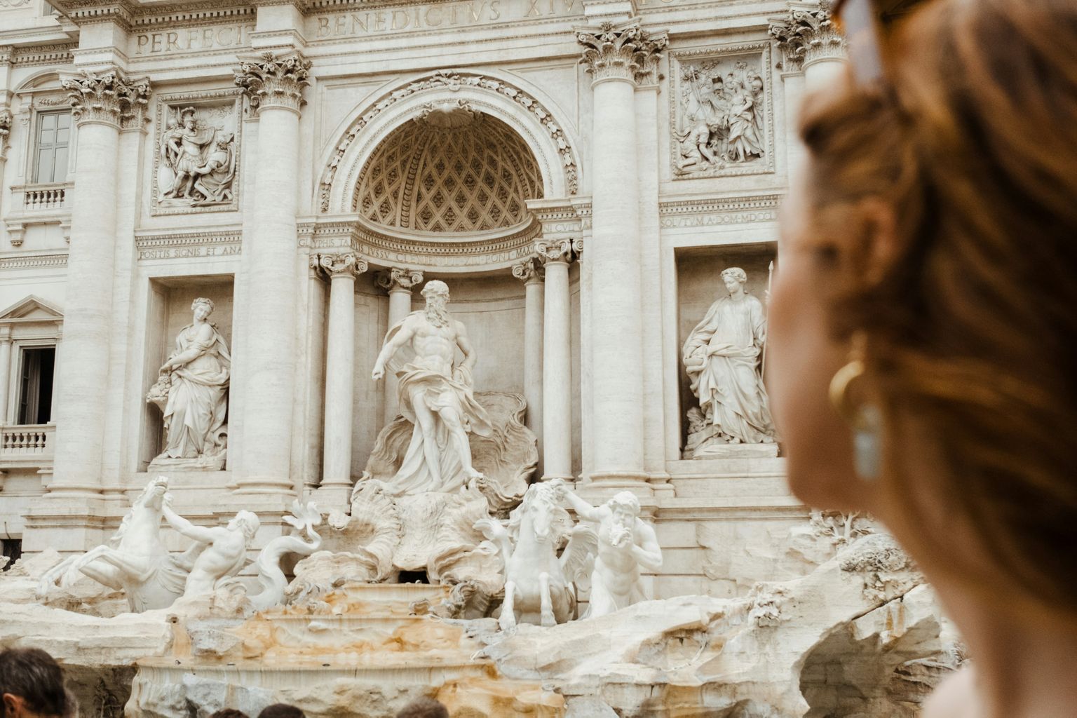 A person gazes at the Trevi Fountain in Rome, with its detailed sculptures and baroque architecture.