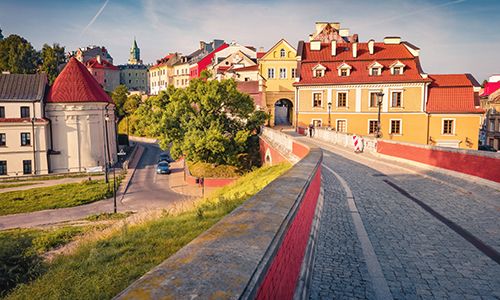 Cobblestone path leading through a historic European town with colorful buildings under a blue sky.