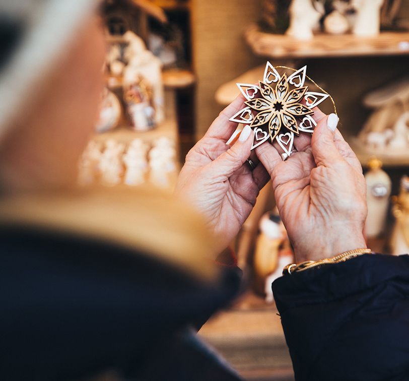 A person holding an intricate, star-shaped ornament at a market stall displaying various nativity scene figures.