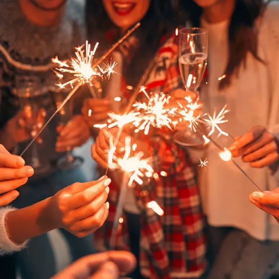 People holding sparklers and champagne glasses, celebrating together in festive attire.