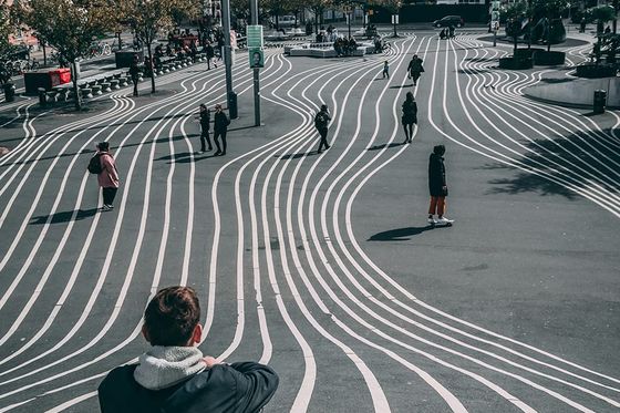A person sitting on a pedestrian street painted with wavy white lines
