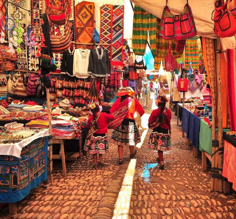 A group of people walking in a market full of colorful textiles