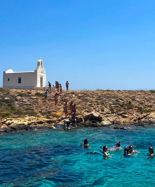 People swimming in the ocean with a single white building in the background
