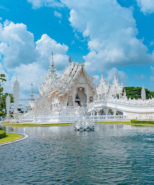 A white temple on the water in Thailand.