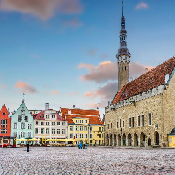 A picturesque town square with colorful historic buildings, a tall spire, and a cobblestone ground beneath a vibrant sky.