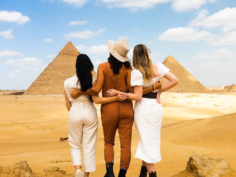 Three women standing in front of the Great Pyramid of Giza