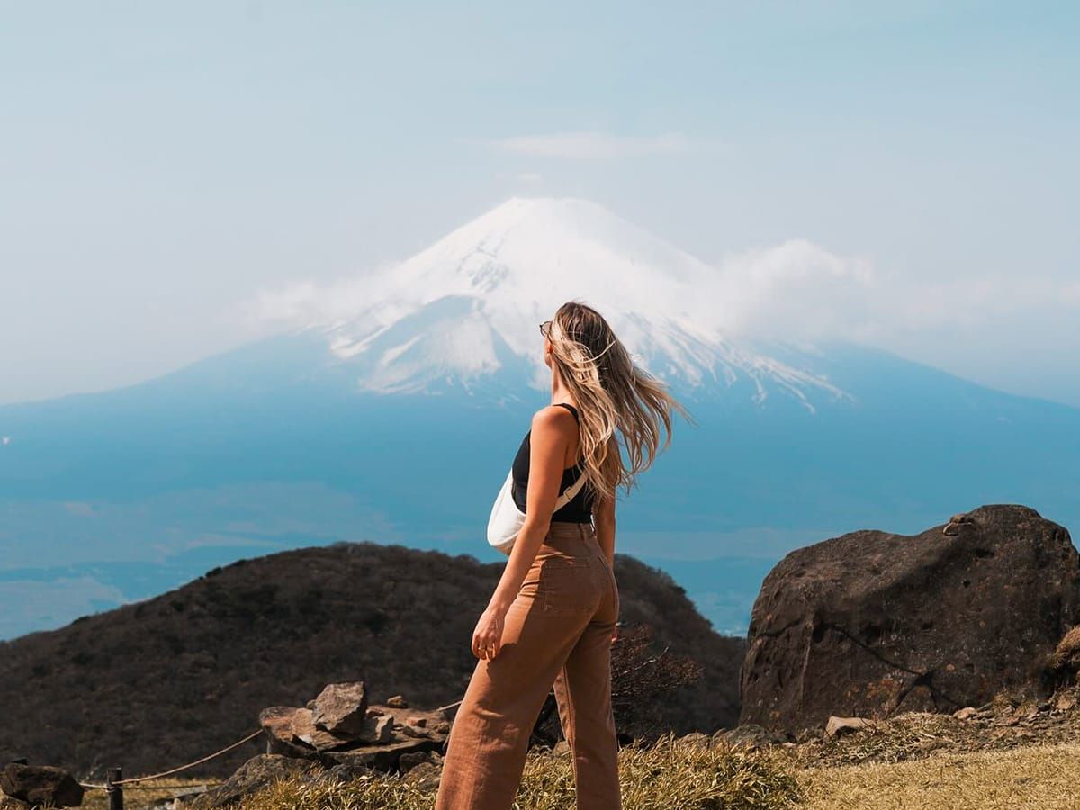 A person facing away from the camera looking out toward a large snow-capped mountain