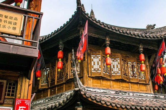 Traditional Chinese building with ornate wooden architecture, red lanterns, and intricate roof details against a blue sky.