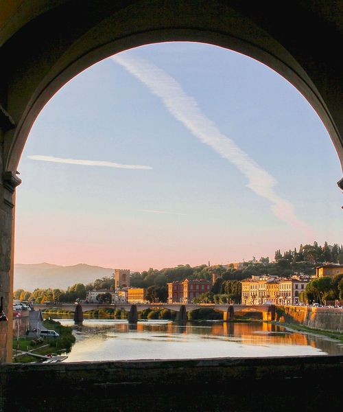 A view of the Arno River as seen through a stone arch on the Ponte Vecchio