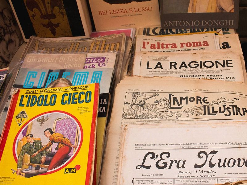A collection of vintage Italian magazines and newspapers with colorful covers and Italian text, displayed in a market stall.