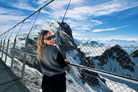 A person standing on a bridge over a snowy mountain